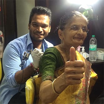 Tattoo Artist Swapnil Parab with happy elderly client showing thumbs to camera